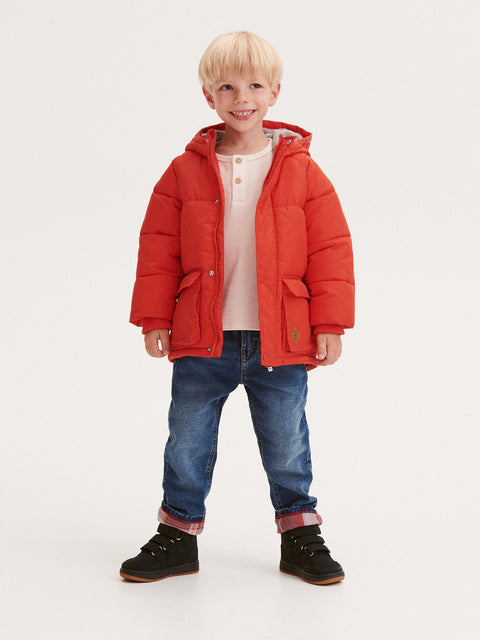 Child wearing a red puffer jacket on a white background
