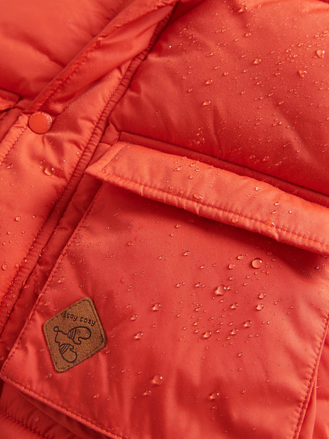 Close-up of a red puffer jacket with water droplets on the surface, featuring a brand logo.