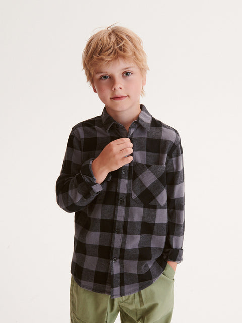 Young boy wearing a black and gray checkered shirt on a white background
