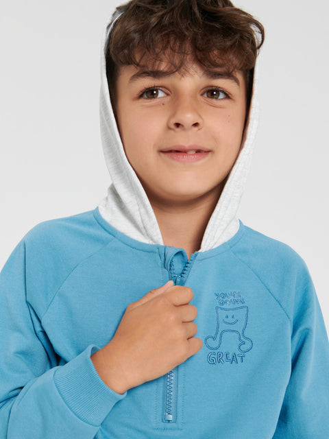 Child wearing a blue hoodie with a smiley face design on a white background