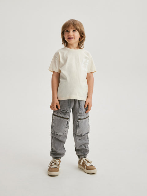 Child wearing a white t-shirt and gray cargo pants on a light background