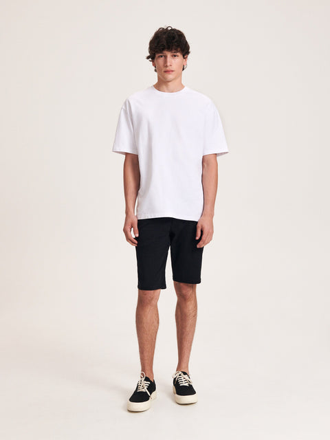 Person wearing a white t-shirt and black shorts on a plain background