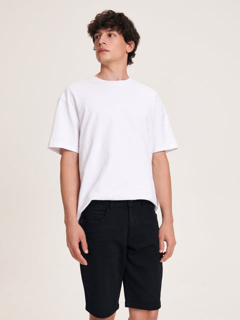 Person wearing a white t-shirt and black shorts on a plain background