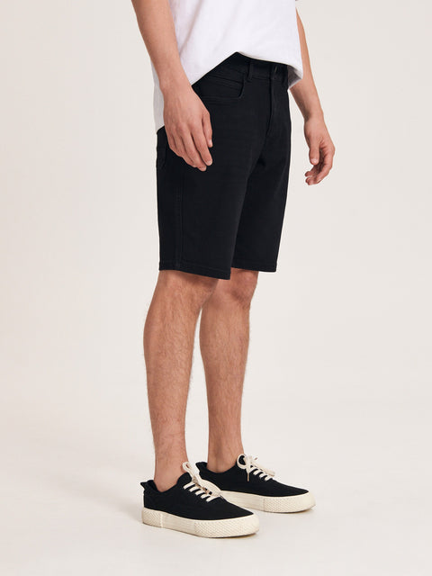 Person wearing black shorts and black sneakers on a white background