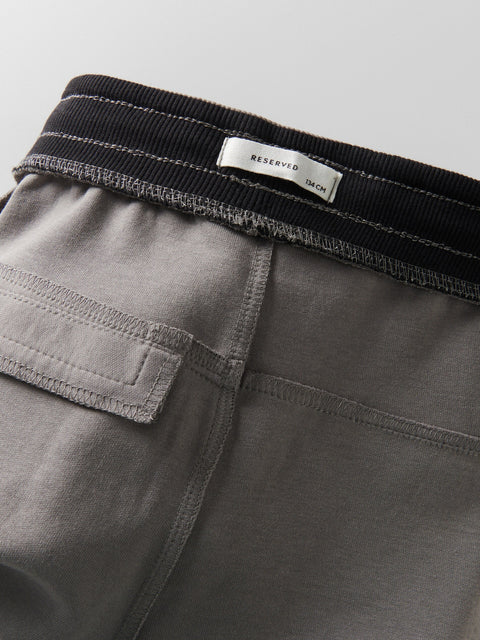 Close-up of gray shorts with a black waistband and a visible brand label.