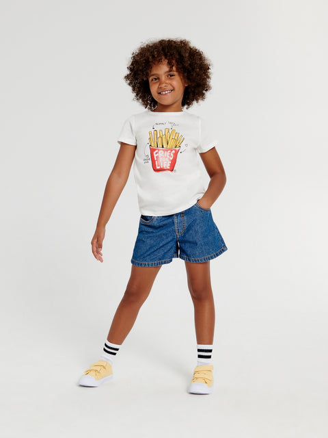 Child wearing a white t-shirt with a graphic design and blue shorts on a light gray background