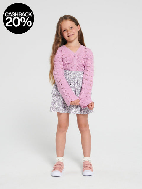 Young girl wearing a pink sweater and silver skirt on a white background with a cashback 20% badge.