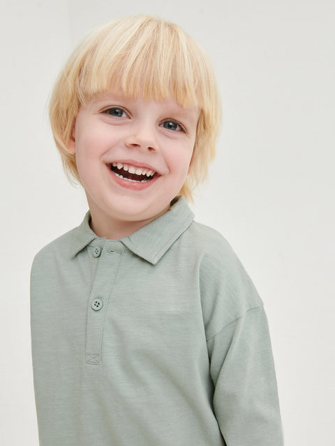 Child wearing a light green polo shirt against a plain background