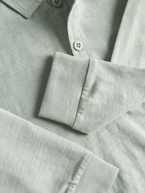 Close-up of a light gray shirt with a buttoned sleeve and collar.