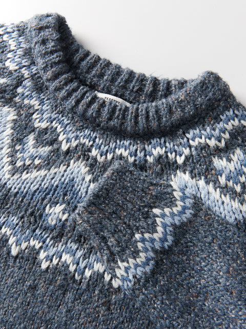 Close-up of a blue knitted sweater with patterned collar and cuffs on a light background