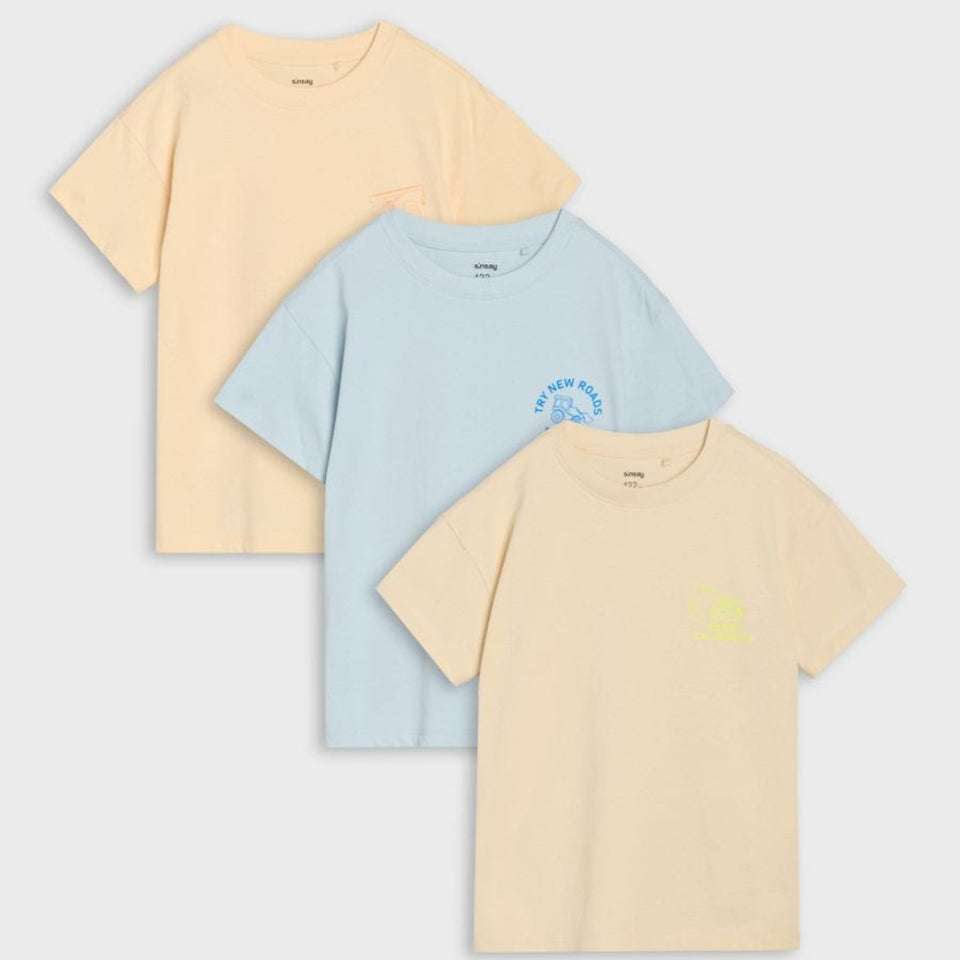 Three short-sleeve crew-neck t-shirts in pastel yellow, light blue, and pale peach, arranged diagonally on a light gray background.