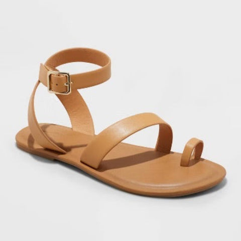 Tan sandal with a gold buckle on a light gray background