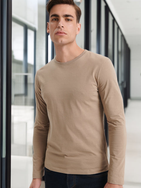 Man wearing a beige long-sleeve shirt in an indoor setting