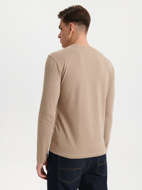 Man wearing a beige long-sleeve shirt on a white background