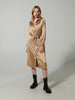 Woman wearing a beige dress with a belt and black boots on a plain background