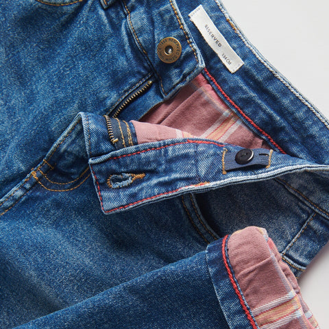 Close-up of a blue denim jacket with pink lining and a visible brand label.