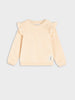 Beige long-sleeve shirt with ruffled shoulders on a light gray background