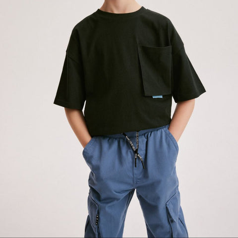 Person wearing a black t-shirt with a pocket and blue pants on a plain background