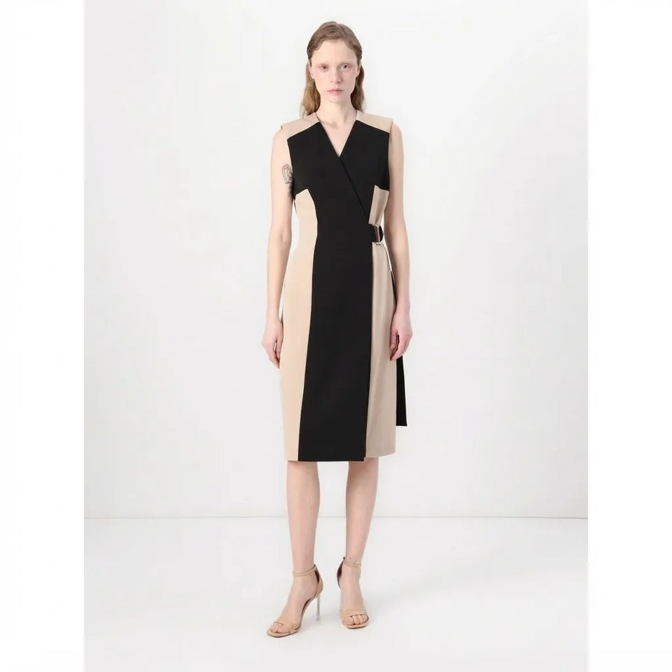 A woman modeling a color-block midi dress with a wrap-style V-neckline, featuring black and beige panels, a matching beige belt, and nude high-heeled sandals against a plain white studio background.