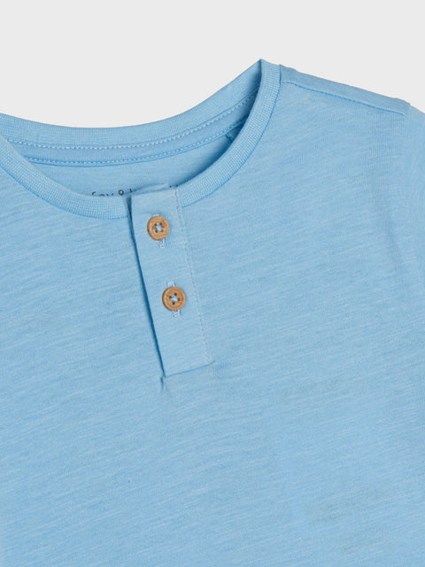 Close-up of a light blue henley shirt with buttons on a white background