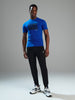 Person wearing a blue t-shirt with 'START DOING' text, black pants, and white sneakers on a gray background