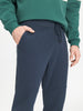 Person wearing a green sweatshirt and navy blue pants on a white background