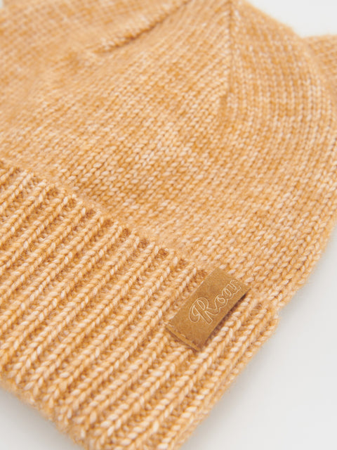 Beige knit beanie with a brand label on a light background