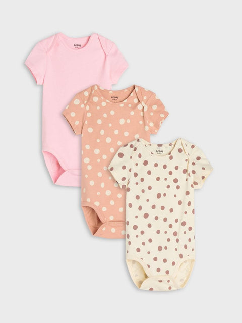 Three baby bodysuits in pink, peach, and cream with polka dot patterns on a white background.