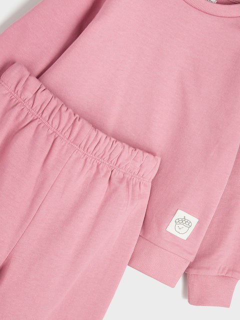 Close-up of a pink sweatshirt with a brand logo on a white background
