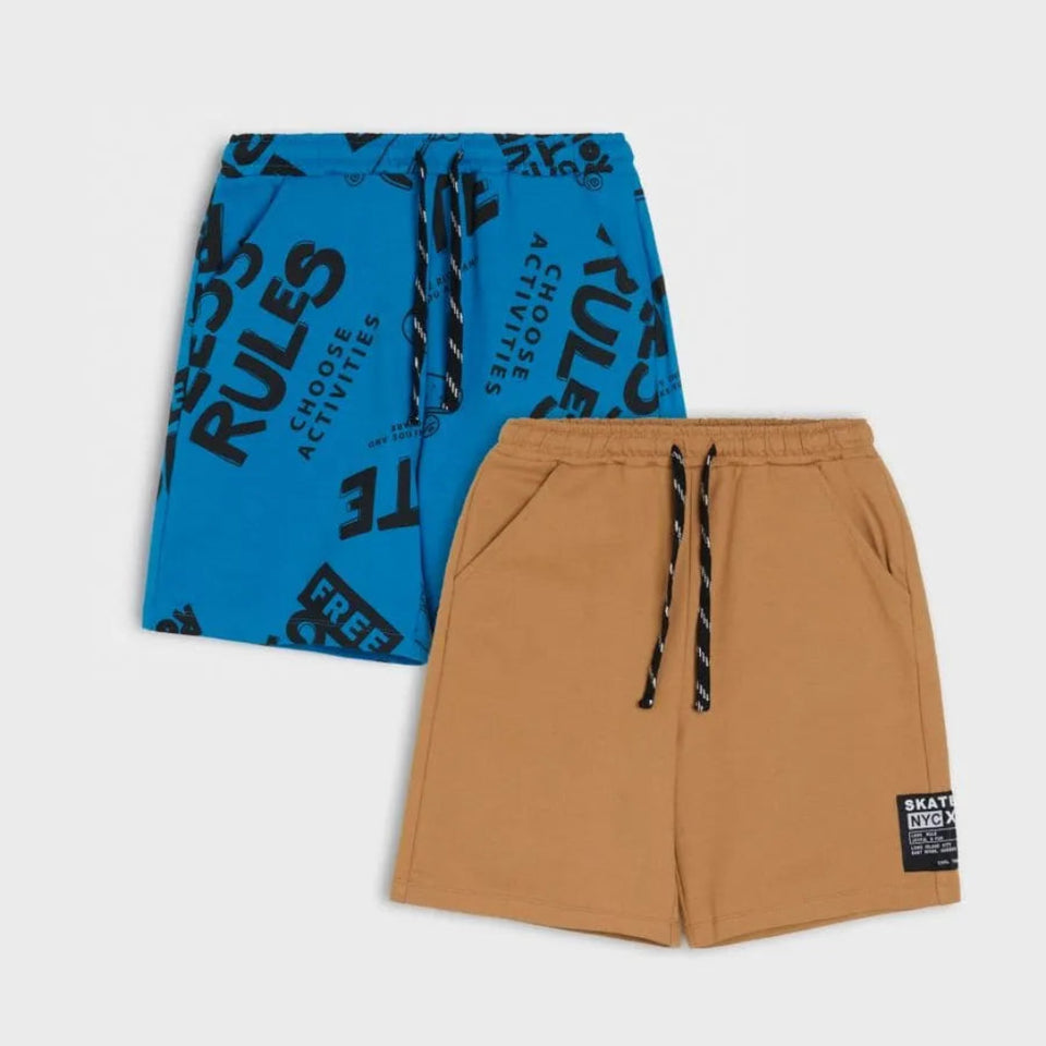 Two pairs of casual shorts from the brand Street, displayed on a light gray background. The top pair is bright blue with black text print and the bottom pair is a warm tan/camel color with black and white striped drawstrings and a small black brand patch on the lower right leg.