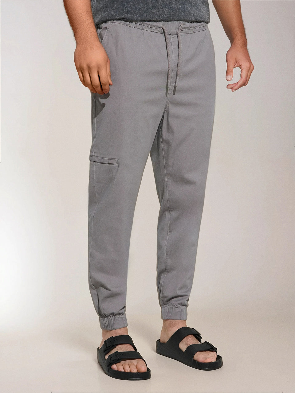 Person wearing gray jogger pants on a plain background
