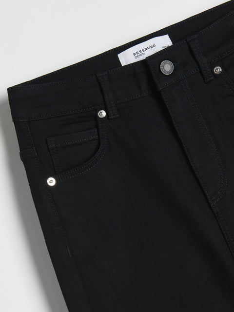 Close-up of black pants with a 'RESERVED' label on a light gray background