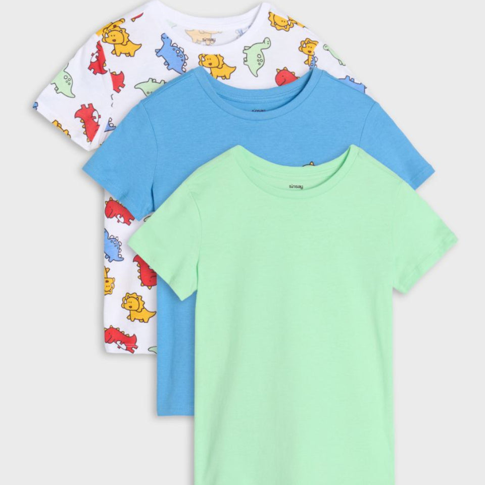 Three children's short-sleeve t-shirts stacked in a fan arrangement on a light gray background. The front shirt is light mint green, the middle shirt is light blue, and the back shirt is white with a colorful dinosaur print.