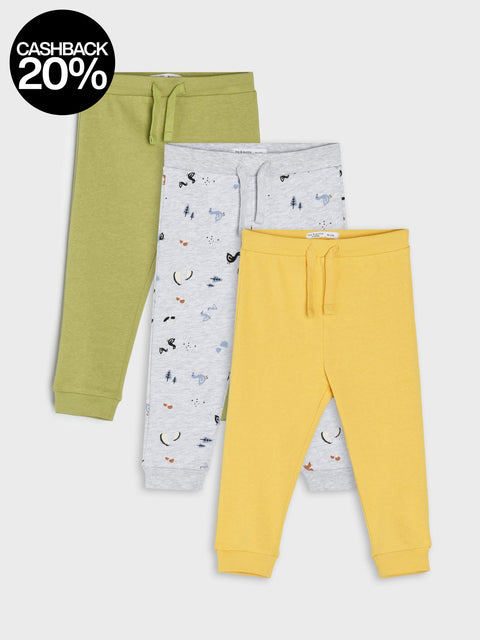 Three pairs of children's jogger pants in green, gray with animal print, and yellow on a light gray background.