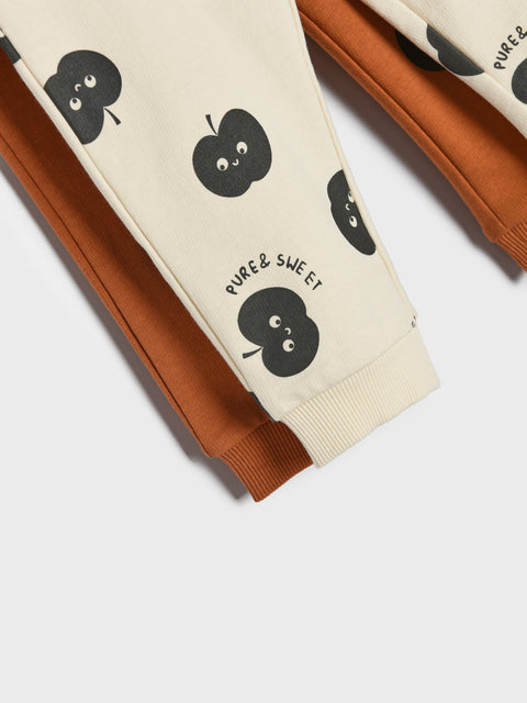Children's pants with apple design and 'PURE & SWEET' text on a white background
