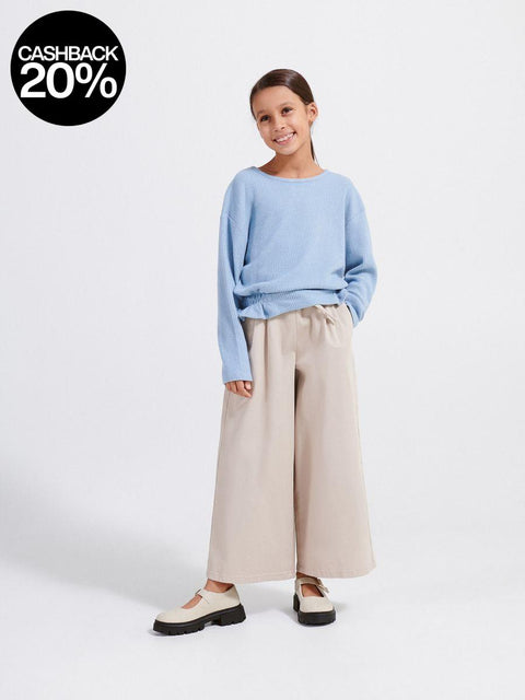 Person wearing a light blue sweater and beige pants on a white background