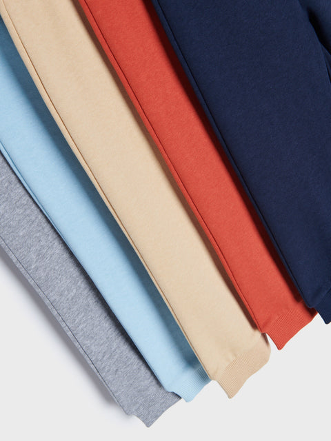 Stack of folded fabric in various colors including gray, blue, beige, red, and navy.