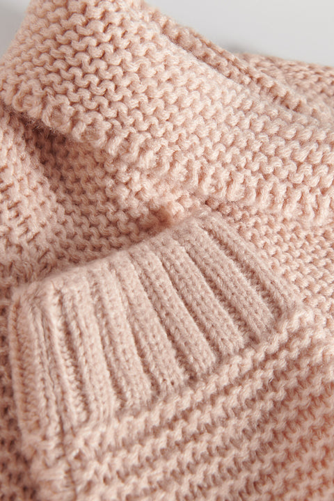 Close-up of a pink knitted sweater with a focus on texture and pattern.