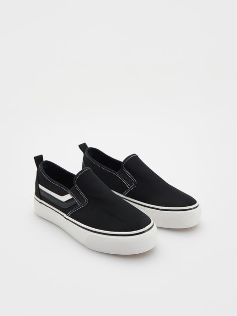 Black slip-on sneakers with white soles on a light gray background