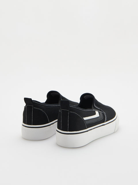 Black slip-on sneakers with white soles on a light gray background