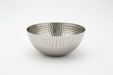 Metallic bowl with textured surface on a wooden surface