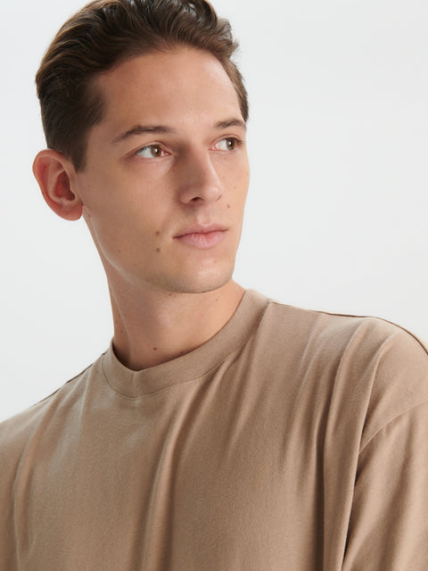 Man wearing a beige long-sleeve shirt against a white background