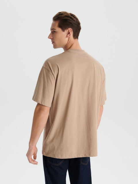 Man wearing a beige t-shirt on a plain background