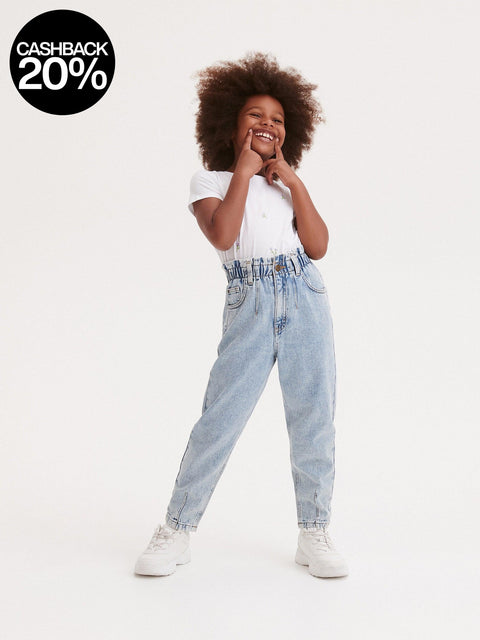 Child wearing a white t-shirt and light blue jeans on a white background
