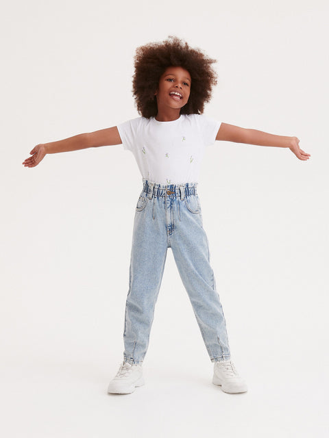 Child wearing a white t-shirt and light blue jeans with arms outstretched on a white background