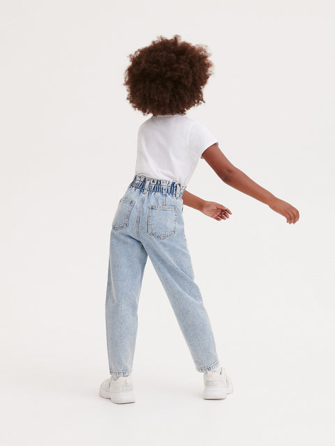 Person wearing light blue jeans and a white shirt on a white background