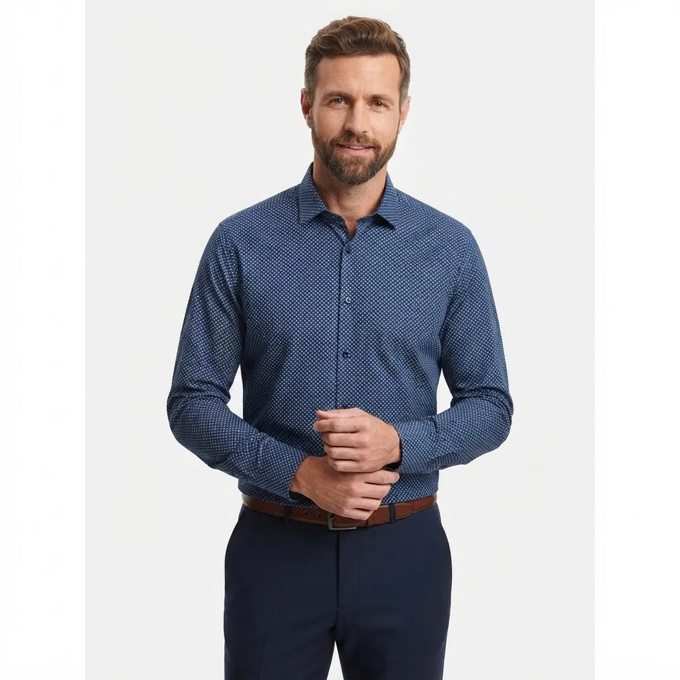 A man wearing a blue long-sleeve button-down shirt with a subtle geometric pattern, paired with navy trousers and a brown belt, standing against a light gray background.