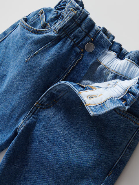 Close-up of blue jeans with a focus on the waistband and hem.