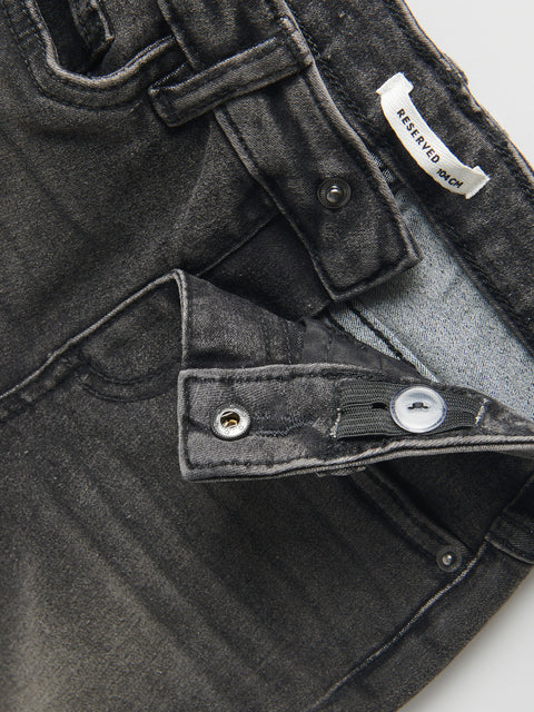 Close-up of a black denim jacket with a brand label on a white background