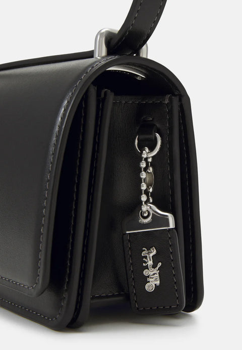 Black handbag with a keychain tag featuring a logo on a white background